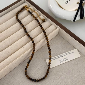 Détail du collier en œil de tigre avec fermoir mousqueton doré sur plateau bijoux