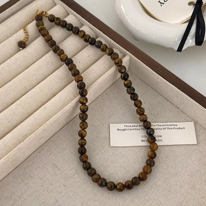 Détail d'un collier en œil de tigre avec fermoir mousqueton doré et chaîne d'extension