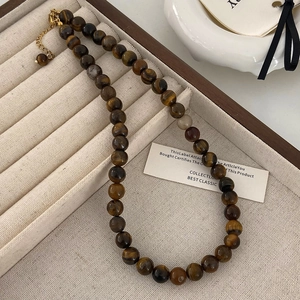 Gros plan d'un collier de perles oeil de tigre 8mm avec fermoir doré sur plateau bijoux
