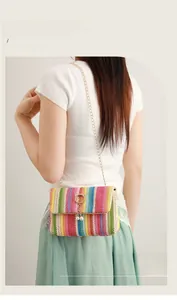 Detail of colorful striped straw crossbody bag with golden cat clasp and pearl charms