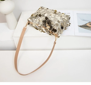 Vue détaillée des paillettes dorées et de la bandoulière beige du sac à l'épaule