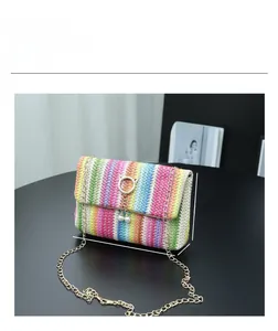 Detail view of woven straw crossbody bag with colorful stripes and pearl tassel charm