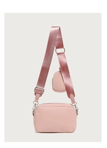 Detailed view of pink crossbody bag with wide strap and matching round coin purse detail