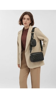 Close-up of black quilted camera bag with a detachable round coin purse on a model