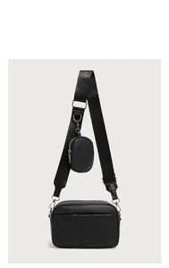 Detail of black quilted camera bag featuring wide woven strap and small round coin purse