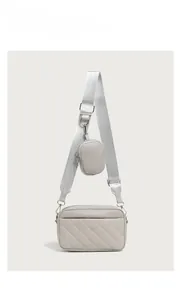 Close-up of quilted camera bag texture with wide strap and circular coin purse detail