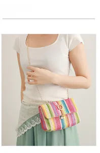Detail of colorful woven crossbody bag with gold chain and pearl buckle pendant
