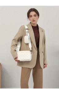 White quilted camera bag featuring adjustable wide strap and a mini cylinder pouch attachment