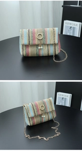 Detail of rainbow straw crossbody bag with golden cat-ear lock and pearl tassel accents