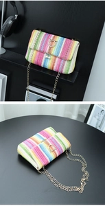 Close-up of colorful straw crossbody bag with gold cat-ear lock and pearl detail