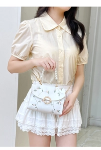 Detailed embroidery and pearl handle on a white floral crossbody bag shown with a model