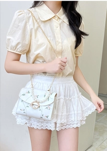 Floral embroidery bag with pearl handle and metal ring detail shown on a model