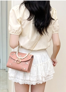 Detailed view of pink floral embroidered crossbody bag with pearl handle and gold chain