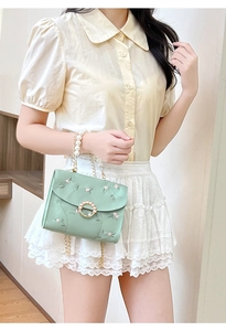 Detailed embroidery of pink flowers and pearl clasp on mint green crossbody bag