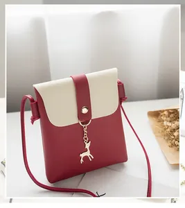 Detail showing the red and beige patchwork PU leather crossbody bag with deer charm
