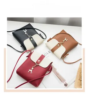 Flat lay of small crossbody bags in red, brown and black with deer pendant charm