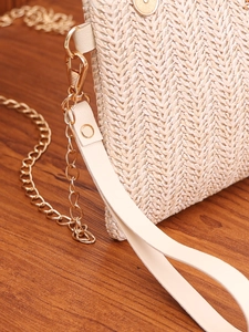 Detail of beige woven straw handbag with gold chain strap and textured fabric finish