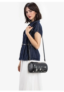 Détail d'un sac cylindrique noir avec broderie florale et fermeture éclair en métal