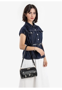 Détail de broderie florale sur sac cylindre noir avec plaque dorée et bandoulière en cuir