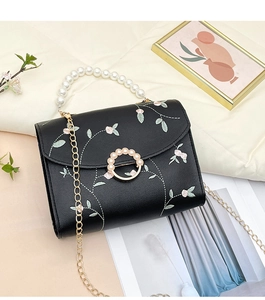 Close-up of floral embroidery and pearl handle on a black crossbody square bag