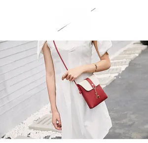Outdoor model display of a burgundy and cream color-block crossbody bag with deer charm