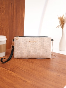 Detailed view of woven beige mini envelope bag with gold chain strap on a wooden desk