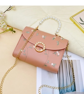 Detailed view of floral embroidery and pearl handle on pink crossbody bag