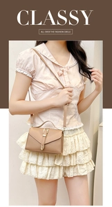 Detail of light brown crossbody bag with gold buckle and adjustable strap on a model