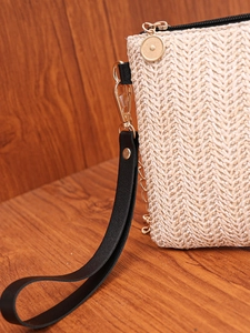 Close-up of beige woven clutch bag with black wrist strap and gold metal hardware