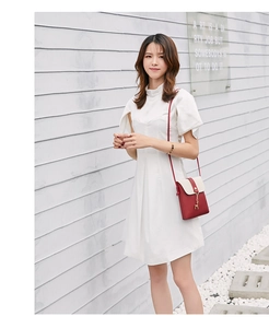Chic red and beige crossbody bag with deer pendant shown on model in street setting