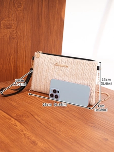 Detail of woven straw handbag featuring gold chain strap and metal logo on wood surface