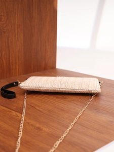 Detail of woven square bag with V-pattern texture and gold chain strap in beige