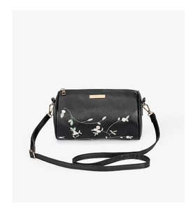 Détails de broderie de fleurs roses et feuilles vertes sur le sac cylindre noir