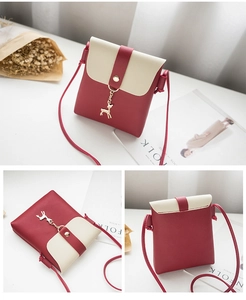 Detail of red and cream contrast mini crossbody bag with gold deer pendant and chain