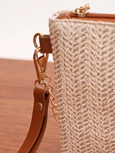 Close-up of woven straw handbag featuring beige textures, brown leather, and gold hardware