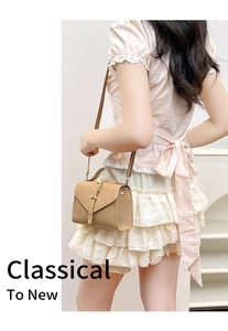 Khaki crossbody square bag with gold buckle and top handle shown in a street style shot