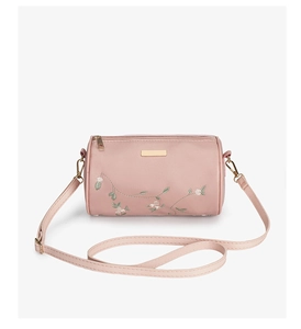 Détail du sac cylindrique rose avec broderie florale et plaque métallique dorée
