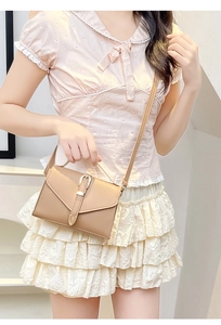 Khaki crossbody bag shown on a model highlighting compact size and minimalist V-flap design