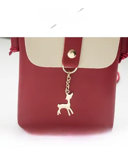 Detailed close-up of a two-tone mini bag with a deer pendant and golden snap fastener
