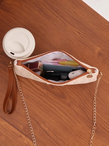 Detail view of woven square bag with brown trim showing interior storage for phone and accessories