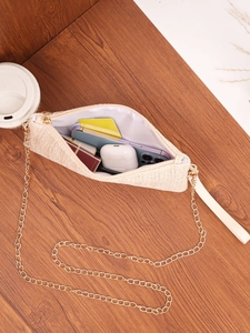Detail of woven crossbody bag interior with gold chain strap holding phone and lipstick