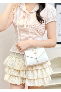 Close-up of stylish white square crossbody bag with gold buckle on female model
