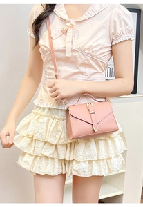 Pink envelope crossbody bag with gold buckle detail and adjustable strap on model