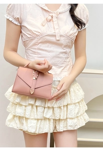 Detail of pink mini square bag with envelope flap and gold metal buckle decoration