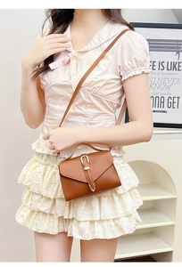 Detail of a vintage brown leather crossbody bag with metal buckle and slim strap