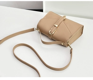 Close-up of khaki leather square bag showing grain texture and gold metal buckles