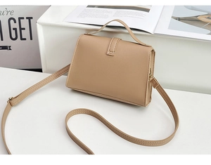 Detail of minimalist beige faux leather crossbody bag with vertical strap and stitching