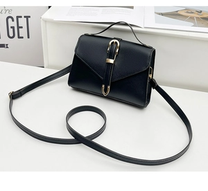 Detail of black pebbled leather crossbody bag with gold hardware and flap closure