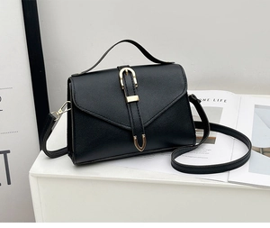 Detail of black litchi texture PU leather handbag with elegant gold U-shaped buckle