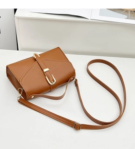 Detail of caramel leather small crossbody bag with elegant golden buckle and shoulder strap